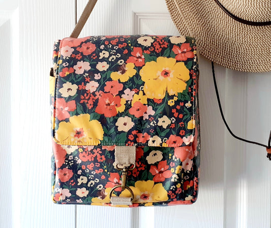 Large lunch bag sewing pattern with front and back pockets, a flap to close, elasticated bottle pocket and insulated lining.