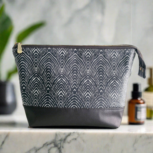 large size toiletry bag in an abstract hills design on a navy background with a dark grey faux leather base.